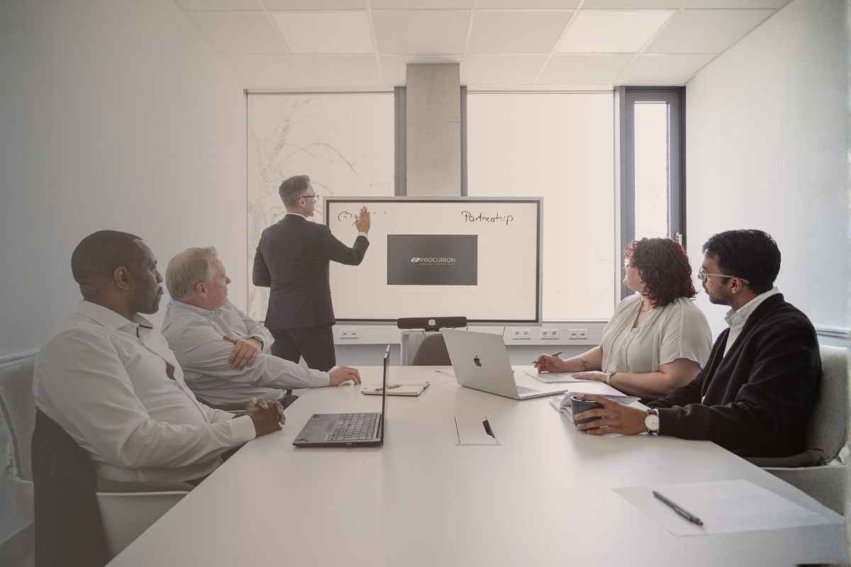 Teammeeting bei Procurion mit Präsentation zu digitaler Beschaffung, ERP-Integration und strategischer Partnerschaft in modernem Konferenzraum.
